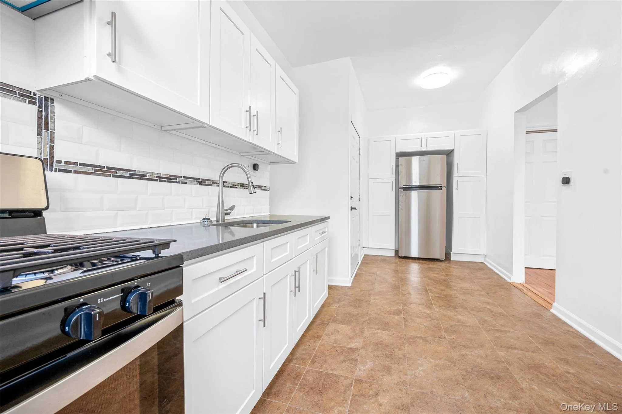 Kitchen featuring appliances with stainless steel finishes, white cabinetry, dark stone countertops, and backsplash Kitchen featuring appliances with stainless steel finishes, white cabinetry, dark stone countertops, and backsplash