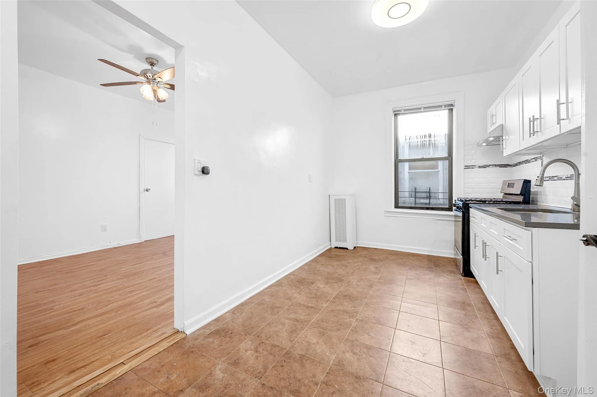 Kitchen featuring white cabinets, dark countertops, stainless steel gas stove, and backsplash Kitchen featuring white cabinets, dark countertops, stainless steel gas stove, and backsplash