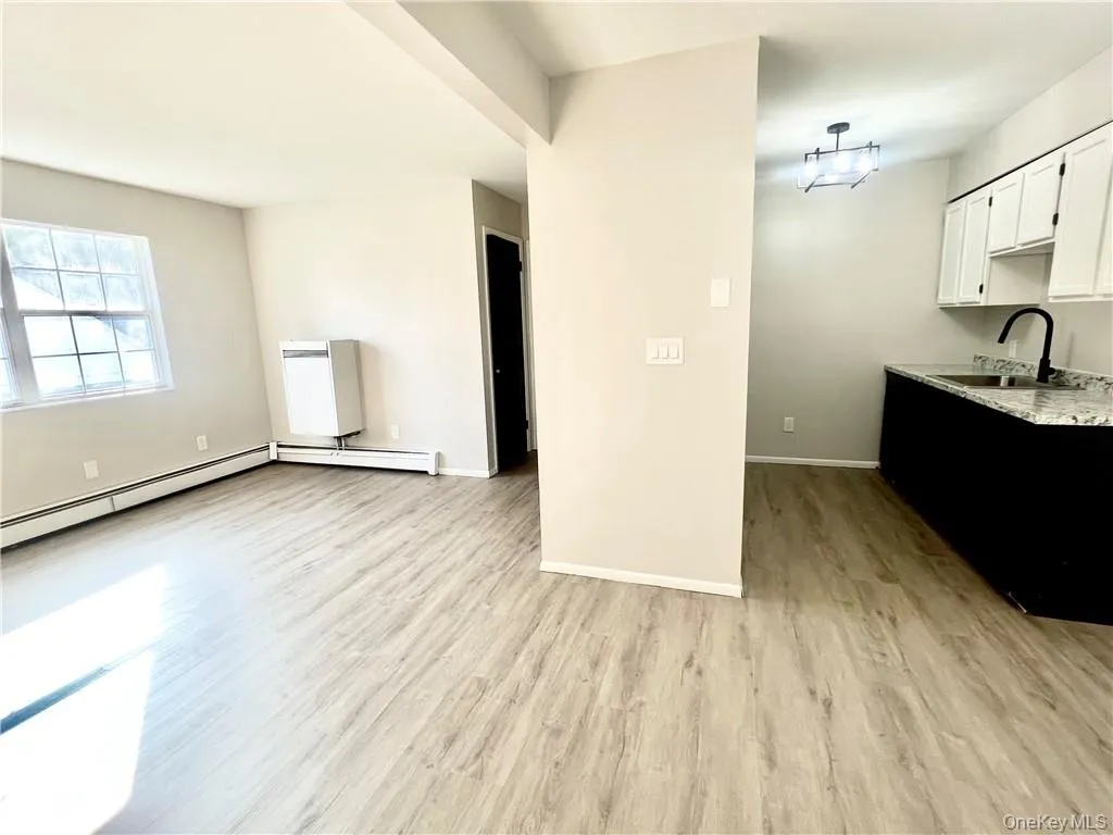 Kitchen with white cabinets, sink, light hardwood / wood-style floors, and a baseboard radiator Kitchen with white cabinets, sink, light hardwood / wood-style floors, and a baseboard radiator