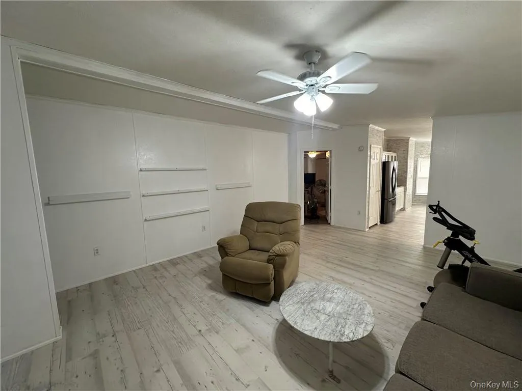 Living room featuring light hardwood / wood-style flooring, ceiling fan, and ornamental molding Living room featuring light hardwood / wood-style flooring, ceiling fan, and ornamental molding