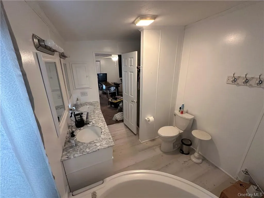 Bathroom featuring vanity, hardwood / wood-style flooring, toilet, and ceiling fan Bathroom featuring vanity, hardwood / wood-style flooring, toilet, and ceiling fan