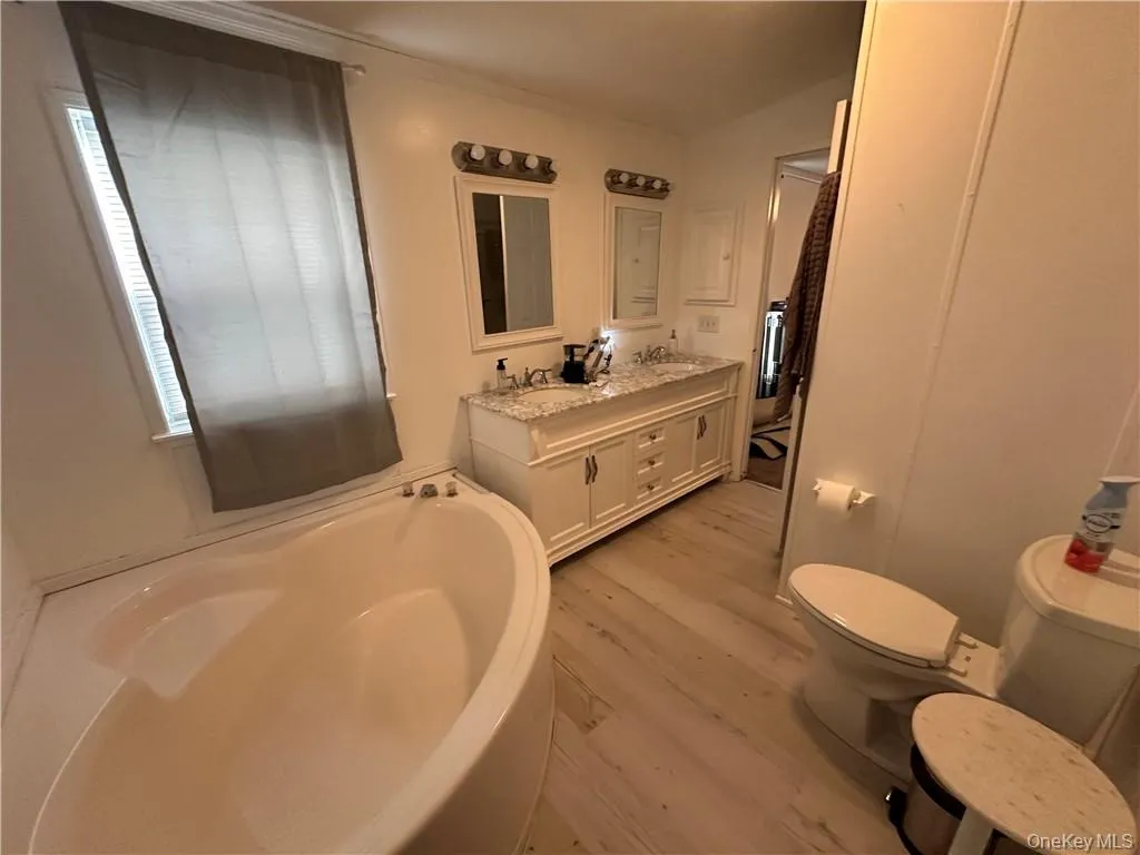 Bathroom featuring vanity, hardwood / wood-style flooring, a bathtub, and toilet Bathroom featuring vanity, hardwood / wood-style flooring, a bathtub, and toilet