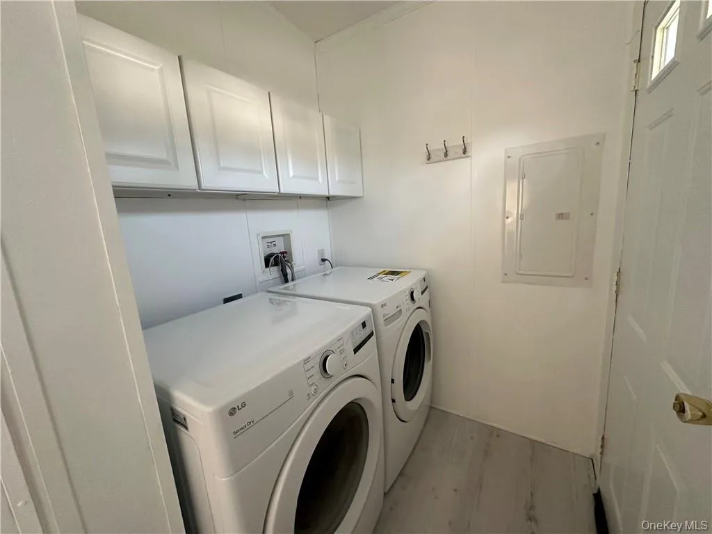 Laundry room featuring light hardwood / wood-style floors, electric panel, independent washer and dryer, and cabinets Laundry room featuring light hardwood / wood-style floors, electric panel, independent washer and dryer, and cabinets