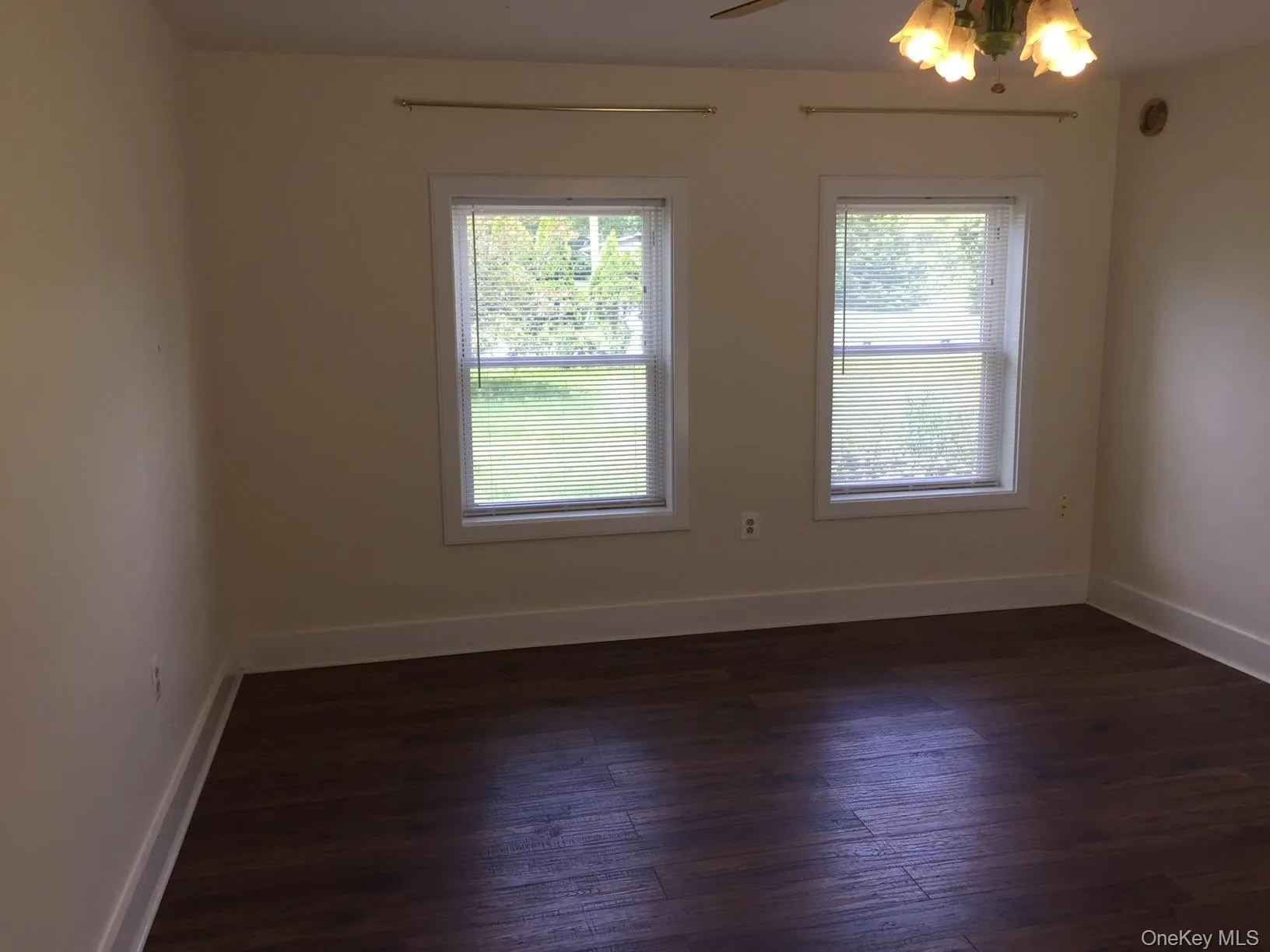 Spare room featuring healthy amount of natural light and dark wood-type flooring Spare room featuring healthy amount of natural light and dark wood-type flooring