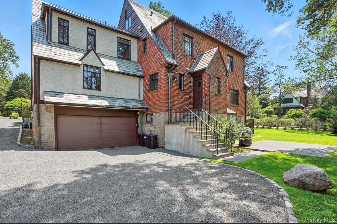 Tudor home with a high end roof, driveway, a garage, and stone siding Tudor home with a high end roof, driveway, a garage, and stone siding