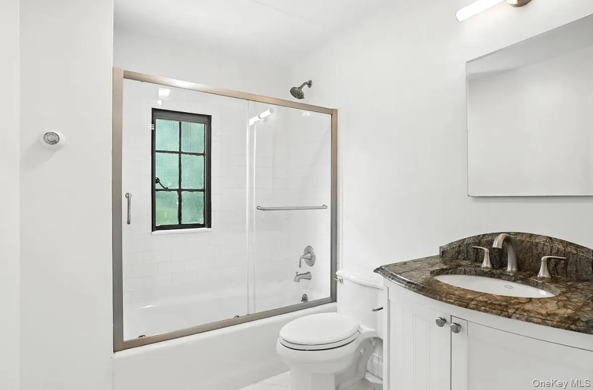 Full bathroom with vanity, enclosed tub / shower combo, and tile patterned floors Full bathroom with vanity, enclosed tub / shower combo, and tile patterned floors