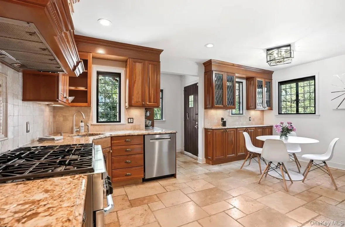 Kitchen with decorative backsplash, ventilation hood, brown cabinets, stainless steel appliances, and recessed lighting Kitchen with decorative backsplash, ventilation hood, brown cabinets, stainless steel appliances, and recessed lighting
