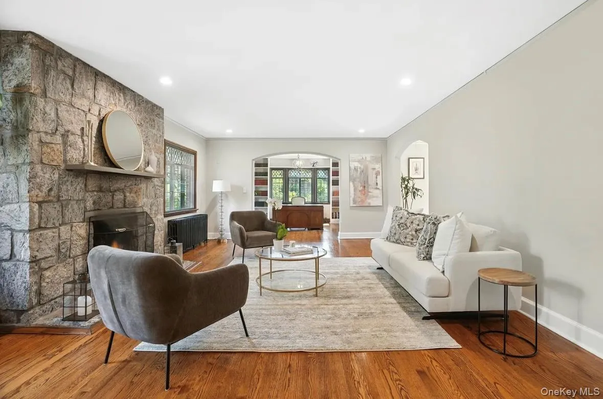 Living room featuring a fireplace, arched walkways, radiator, wood finished floors, and recessed lighting Living room featuring a fireplace, arched walkways, radiator, wood finished floors, and recessed lighting