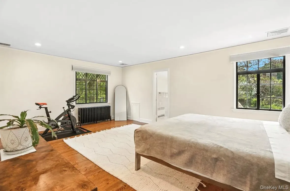 Bedroom featuring wood finished floors, recessed lighting, radiator heating unit, and ensuite bathroom Bedroom featuring wood finished floors, recessed lighting, radiator heating unit, and ensuite bathroom