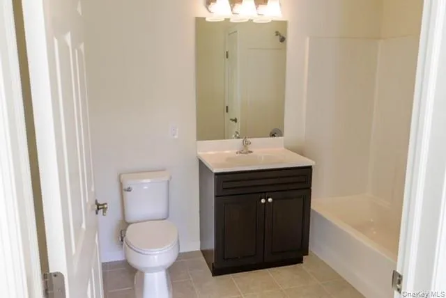 Full bath with vanity, light tile patterned floors, washtub / shower combination, and a chandelier Full bath with vanity, light tile patterned floors, washtub / shower combination, and a chandelier