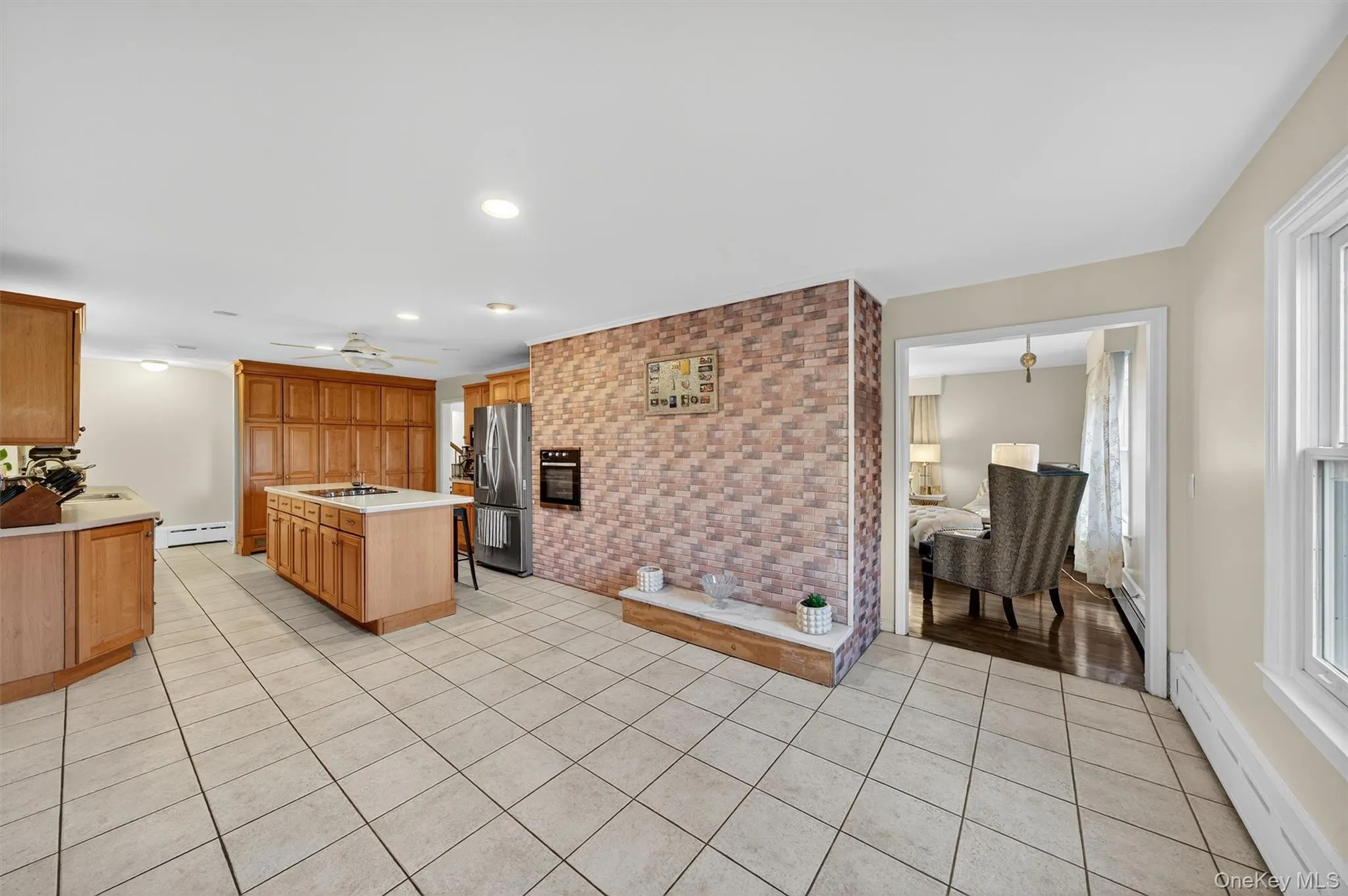 Kitchen featuring baseboard heating, light countertops, light tile patterned floors, a center island, and stainless steel refrigerator with ice dispenser Kitchen featuring baseboard heating, light countertops, light tile patterned floors, a center island, and stainless steel refrigerator with ice dispenser