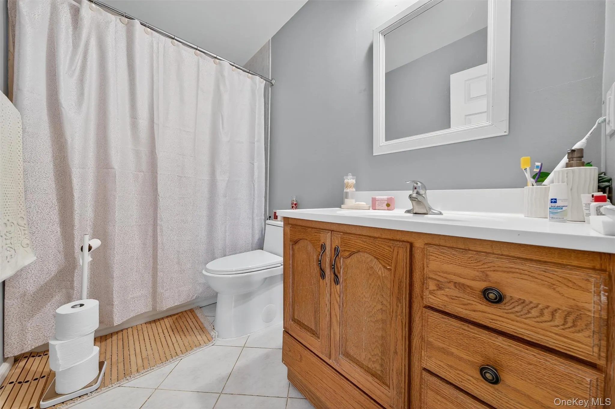 Full bath with vanity, light tile patterned floors, and curtained shower Full bath with vanity, light tile patterned floors, and curtained shower
