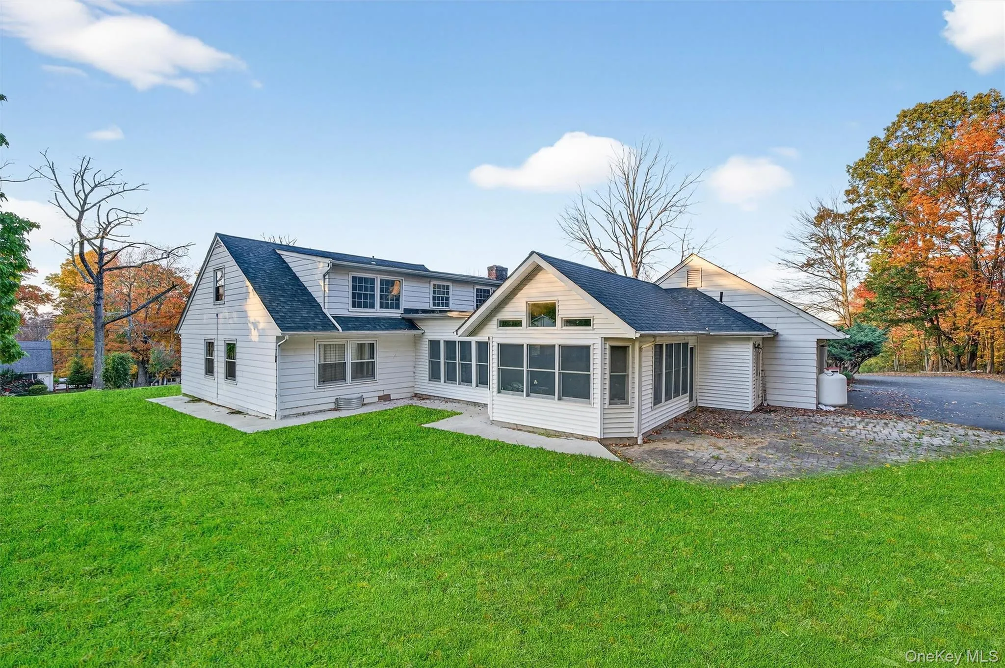 Rear view of property with a sunroom, a lawn, a shingled roof, and a chimney Rear view of property with a sunroom, a lawn, a shingled roof, and a chimney