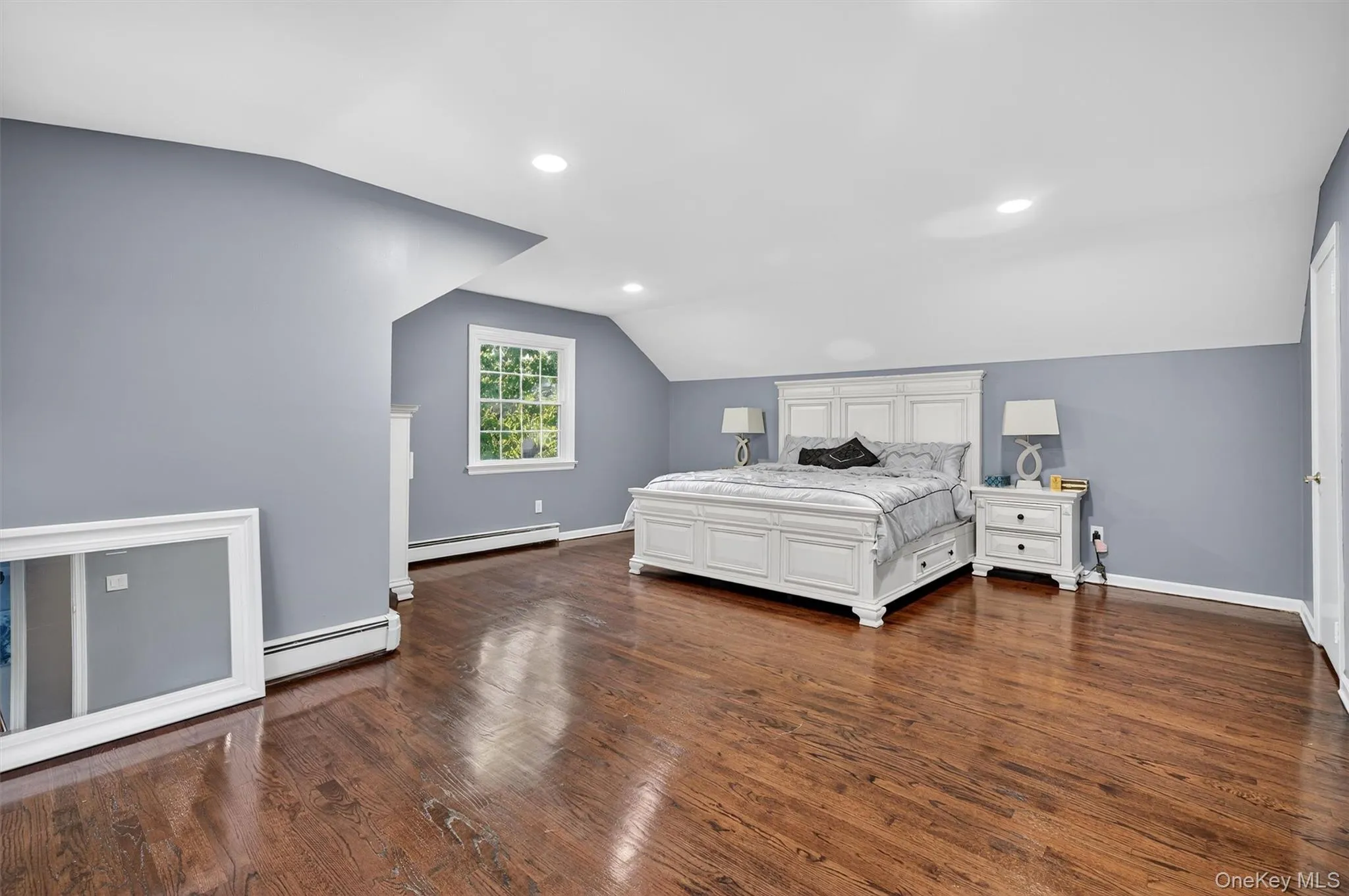 Bedroom with lofted ceiling, dark wood-style floors, a baseboard radiator, and recessed lighting Bedroom with lofted ceiling, dark wood-style floors, a baseboard radiator, and recessed lighting
