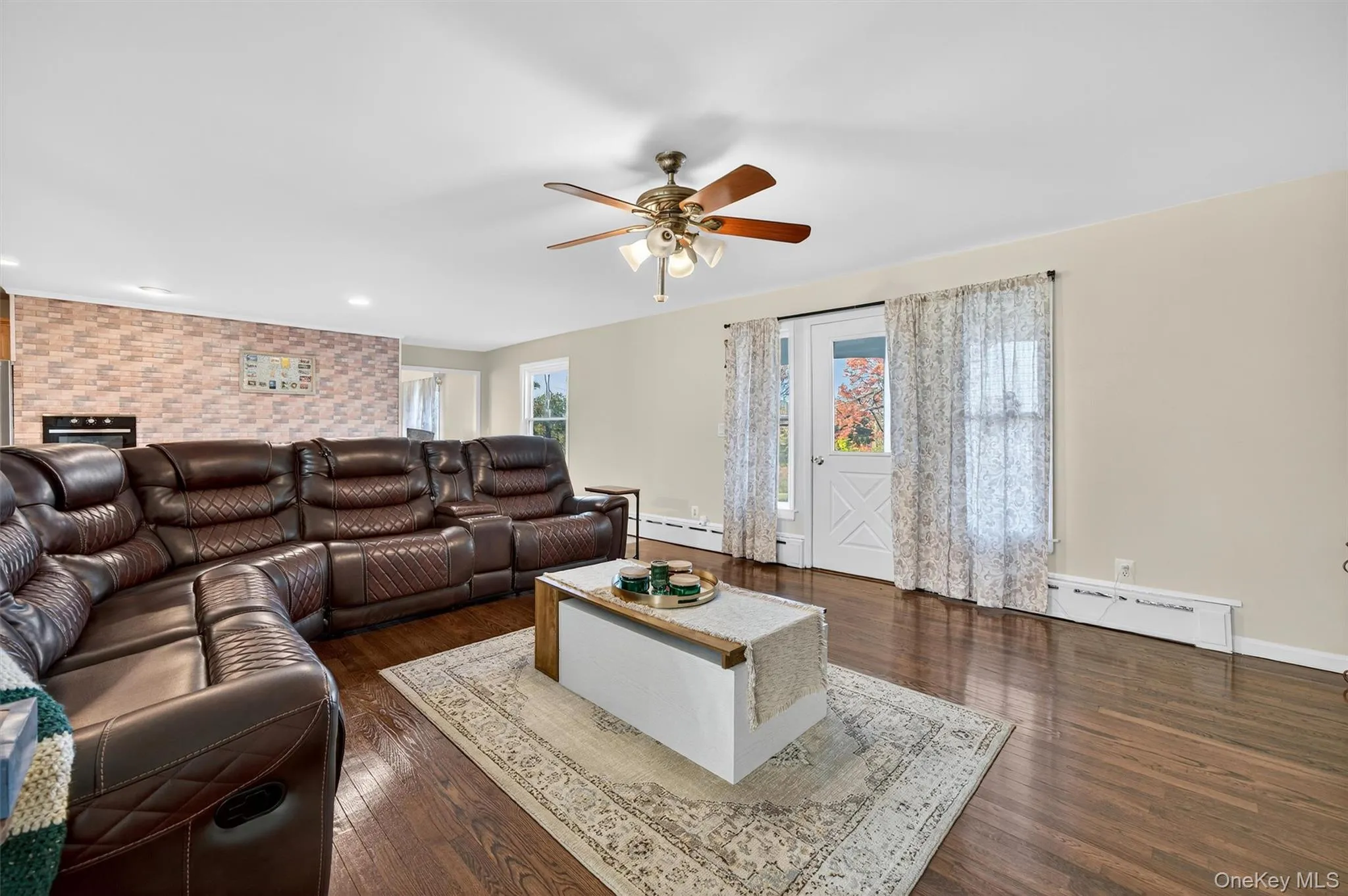 Living room with dark wood-type flooring, a baseboard heating unit, and ceiling fan Living room with dark wood-type flooring, a baseboard heating unit, and ceiling fan