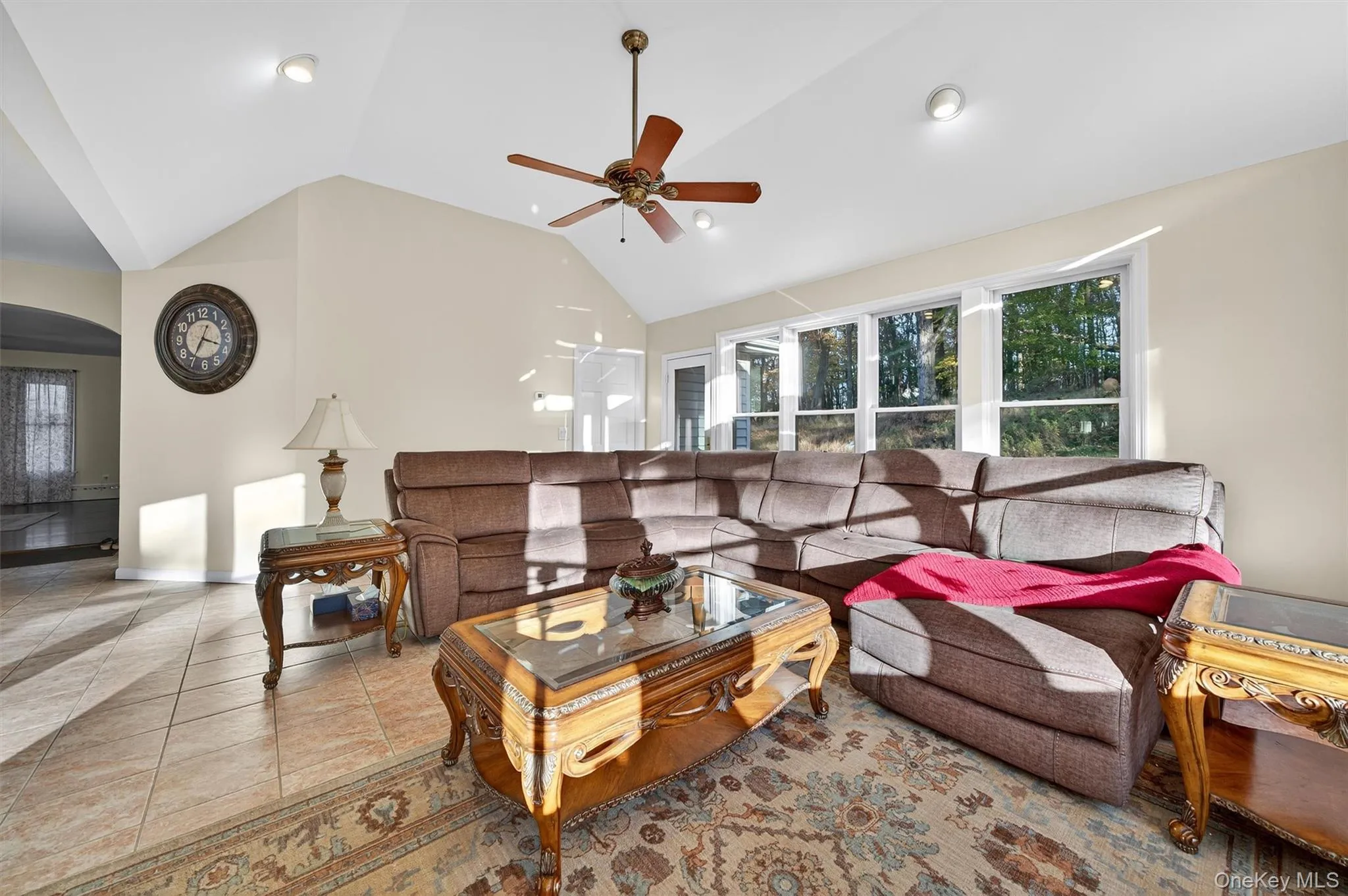 Tiled living room with arched walkways, high vaulted ceiling, and a ceiling fan Tiled living room with arched walkways, high vaulted ceiling, and a ceiling fan