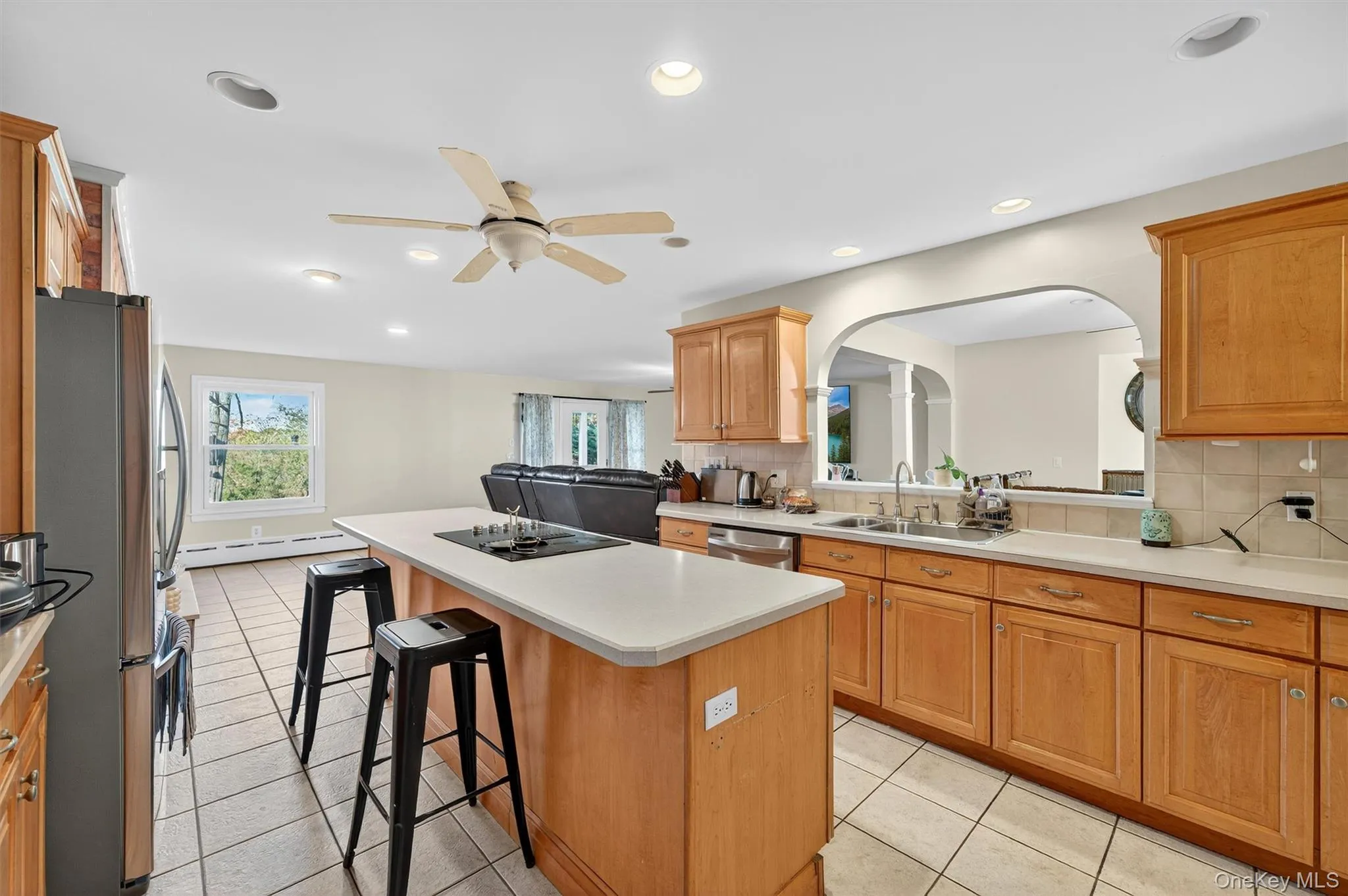 Kitchen with decorative backsplash, light tile patterned floors, a kitchen breakfast bar, appliances with stainless steel finishes, and recessed lighting Kitchen with decorative backsplash, light tile patterned floors, a kitchen breakfast bar, appliances with stainless steel finishes, and recessed lighting