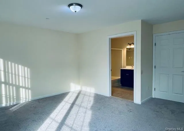 Unfurnished bedroom with carpet and connected bathroom Unfurnished bedroom with carpet and connected bathroom