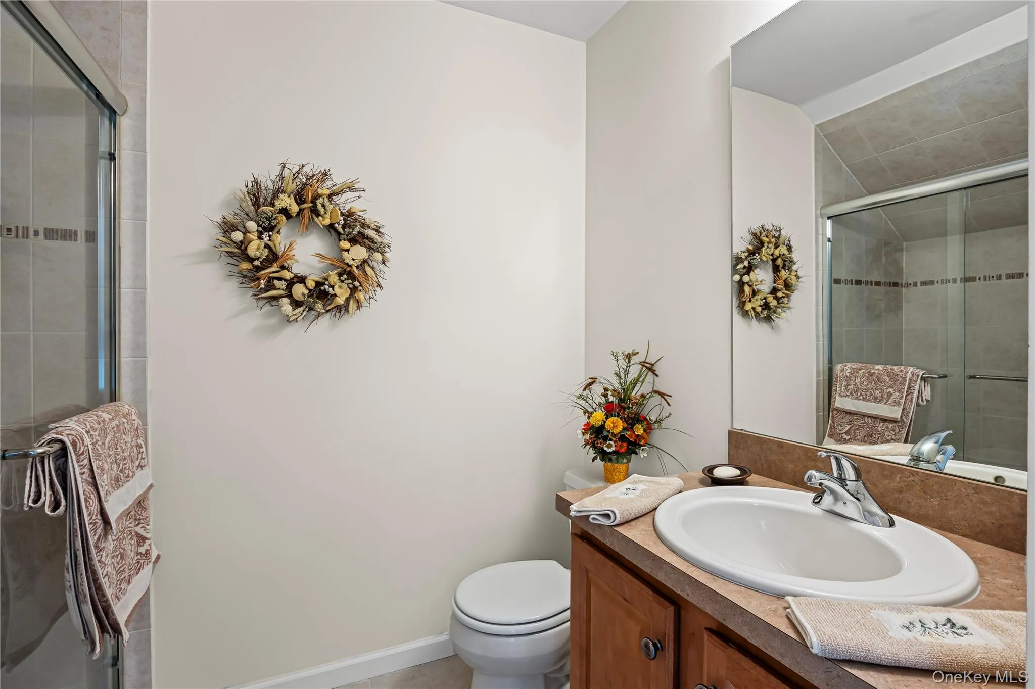 Full bath featuring a stall shower, vanity, and light tile patterned flooring Full bath featuring a stall shower, vanity, and light tile patterned flooring