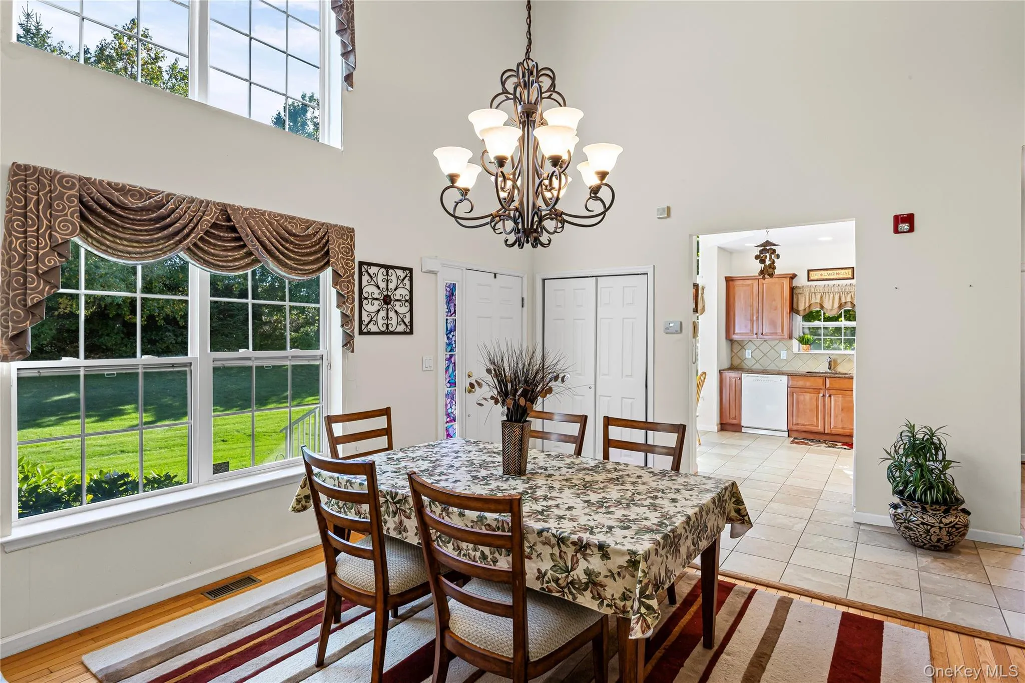 Dining space featuring a towering ceiling, light wood finished floors, and a chandelier Dining space featuring a towering ceiling, light wood finished floors, and a chandelier