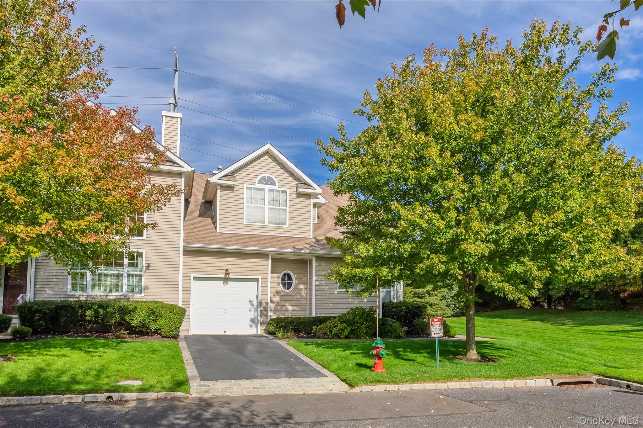 View of front of home featuring a front lawn, driveway, a shingled roof, a garage, and a chimney View of front of home featuring a front lawn, driveway, a shingled roof, a garage, and a chimney