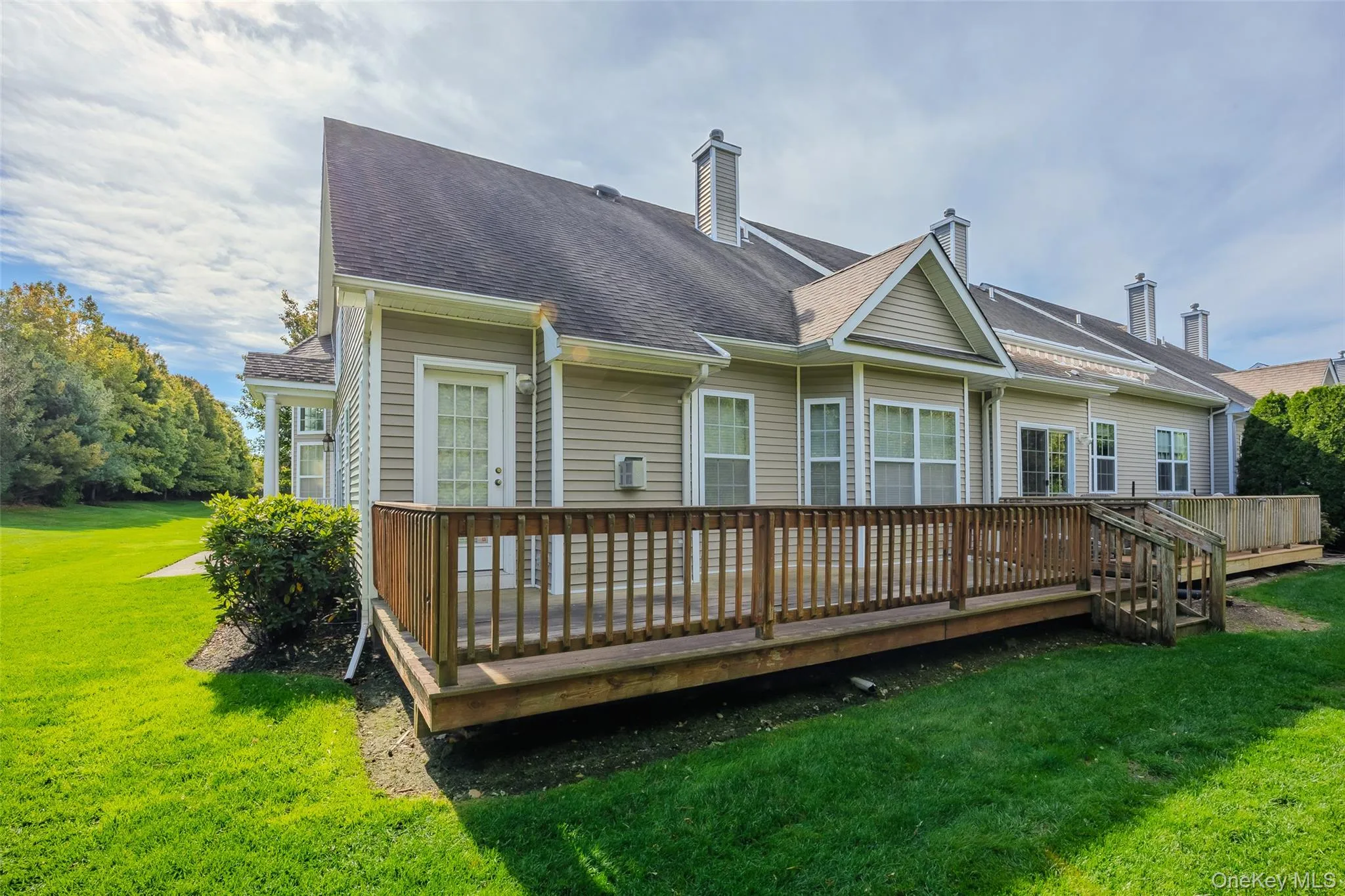 Back of property with a lawn, a wooden deck, a chimney, and a shingled roof Back of property with a lawn, a wooden deck, a chimney, and a shingled roof