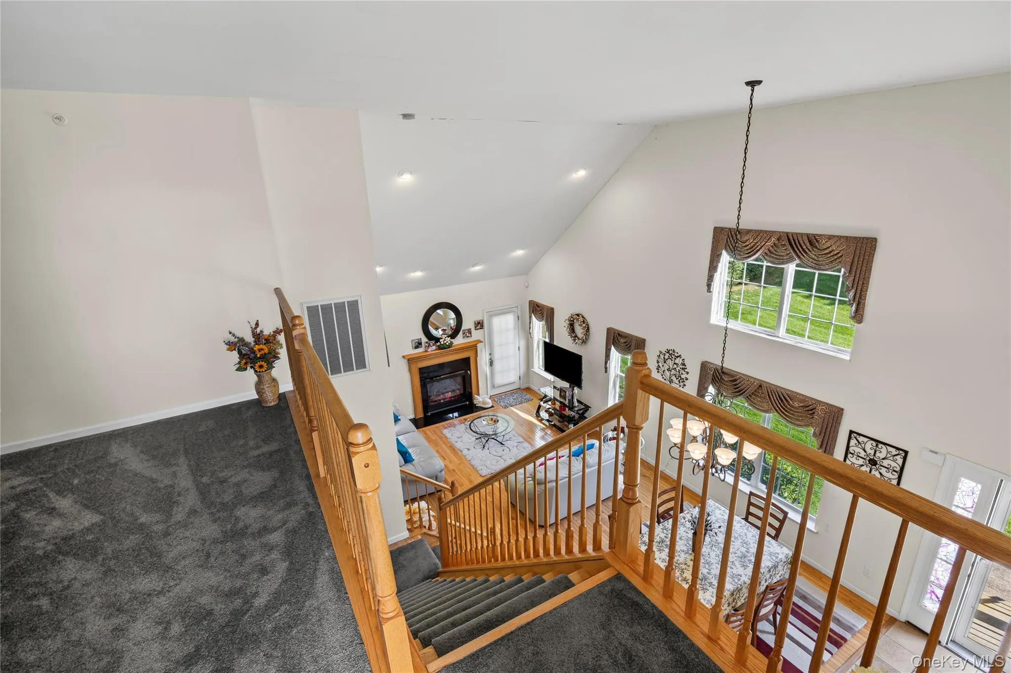 Stairs with high vaulted ceiling, a glass covered fireplace, recessed lighting, and carpet flooring Stairs with high vaulted ceiling, a glass covered fireplace, recessed lighting, and carpet flooring