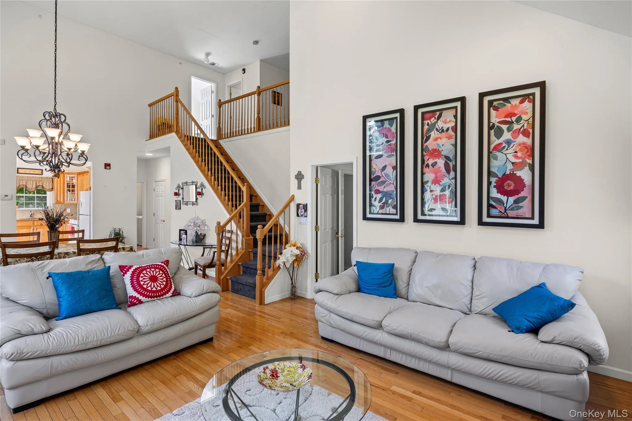 Living room with hardwood / wood-style flooring, stairs, a towering ceiling, plenty of natural light, and a chandelier Living room with hardwood / wood-style flooring, stairs, a towering ceiling, plenty of natural light, and a chandelier