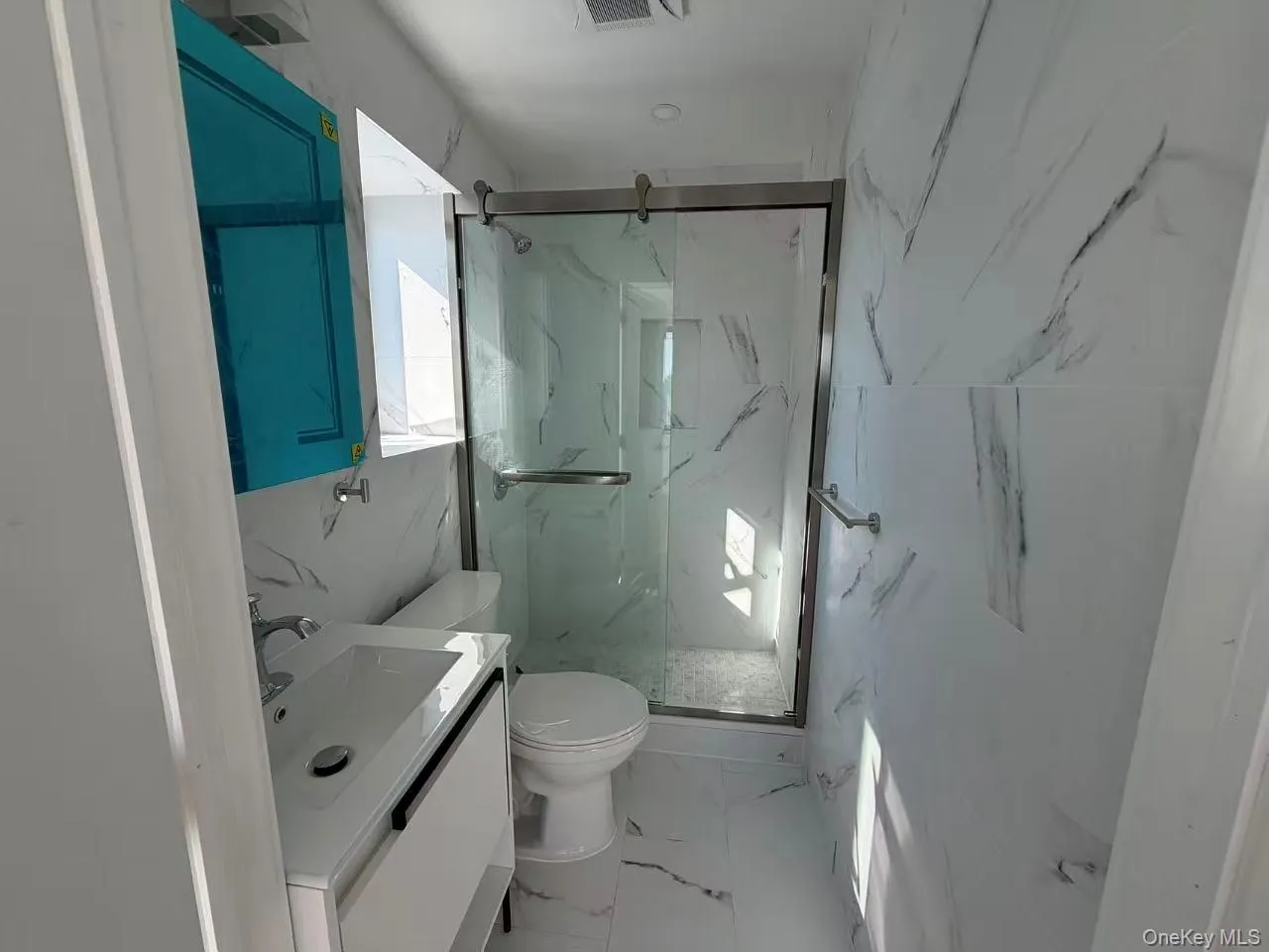 Full bath with vanity, light marble finish floors, a marble finish shower, and stone wall Full bath with vanity, light marble finish floors, a marble finish shower, and stone wall