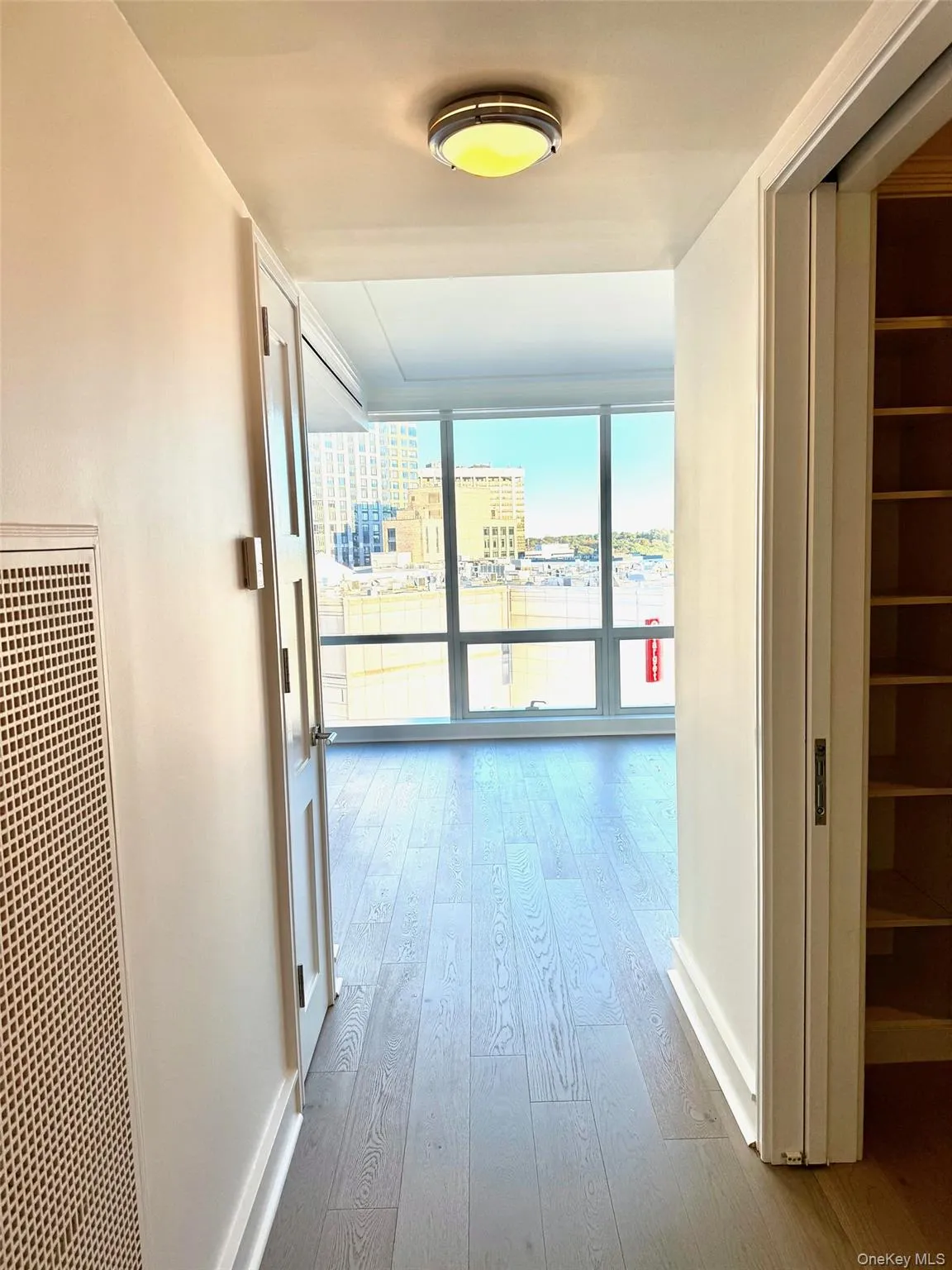Hallway with a wall of windows, a heating unit, light wood-style flooring, and a city view Hallway with a wall of windows, a heating unit, light wood-style flooring, and a city view
