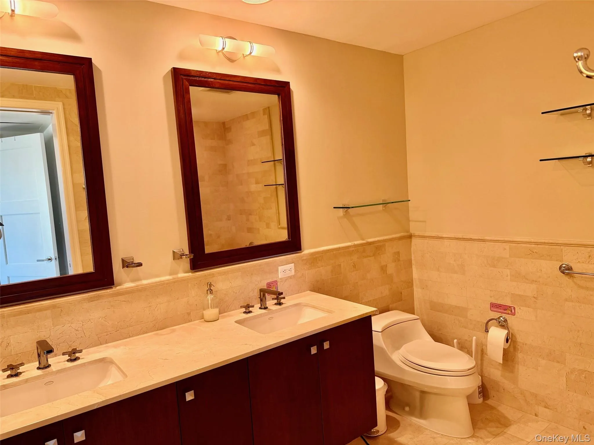 Full bath with tile walls, double vanity, wainscoting, and tile patterned floors Full bath with tile walls, double vanity, wainscoting, and tile patterned floors