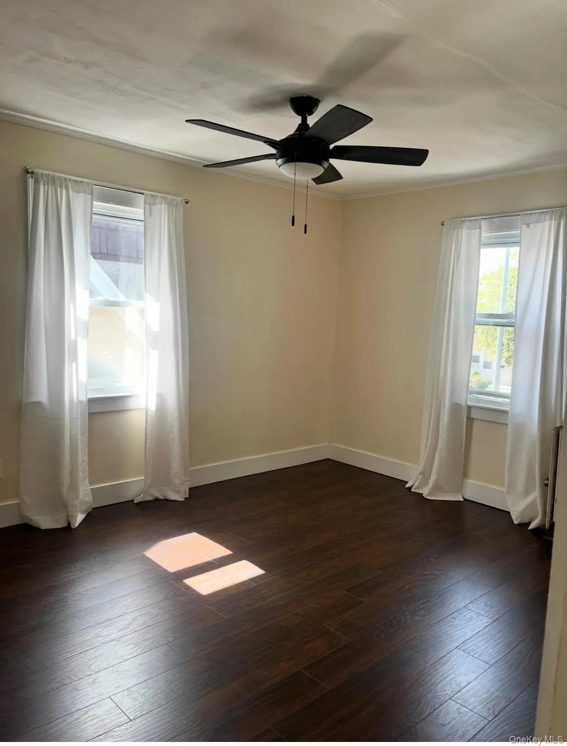 Spare room with dark wood finished floors, ornamental molding, and a ceiling fan Spare room with dark wood finished floors, ornamental molding, and a ceiling fan