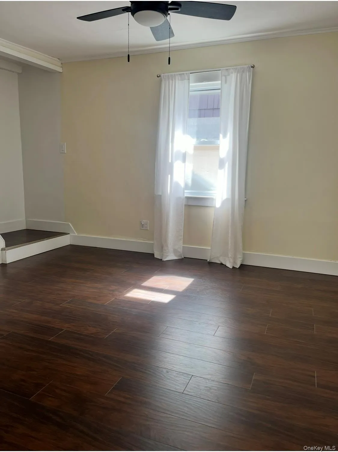 Spare room with crown molding, dark wood finished floors, and a ceiling fan Spare room with crown molding, dark wood finished floors, and a ceiling fan