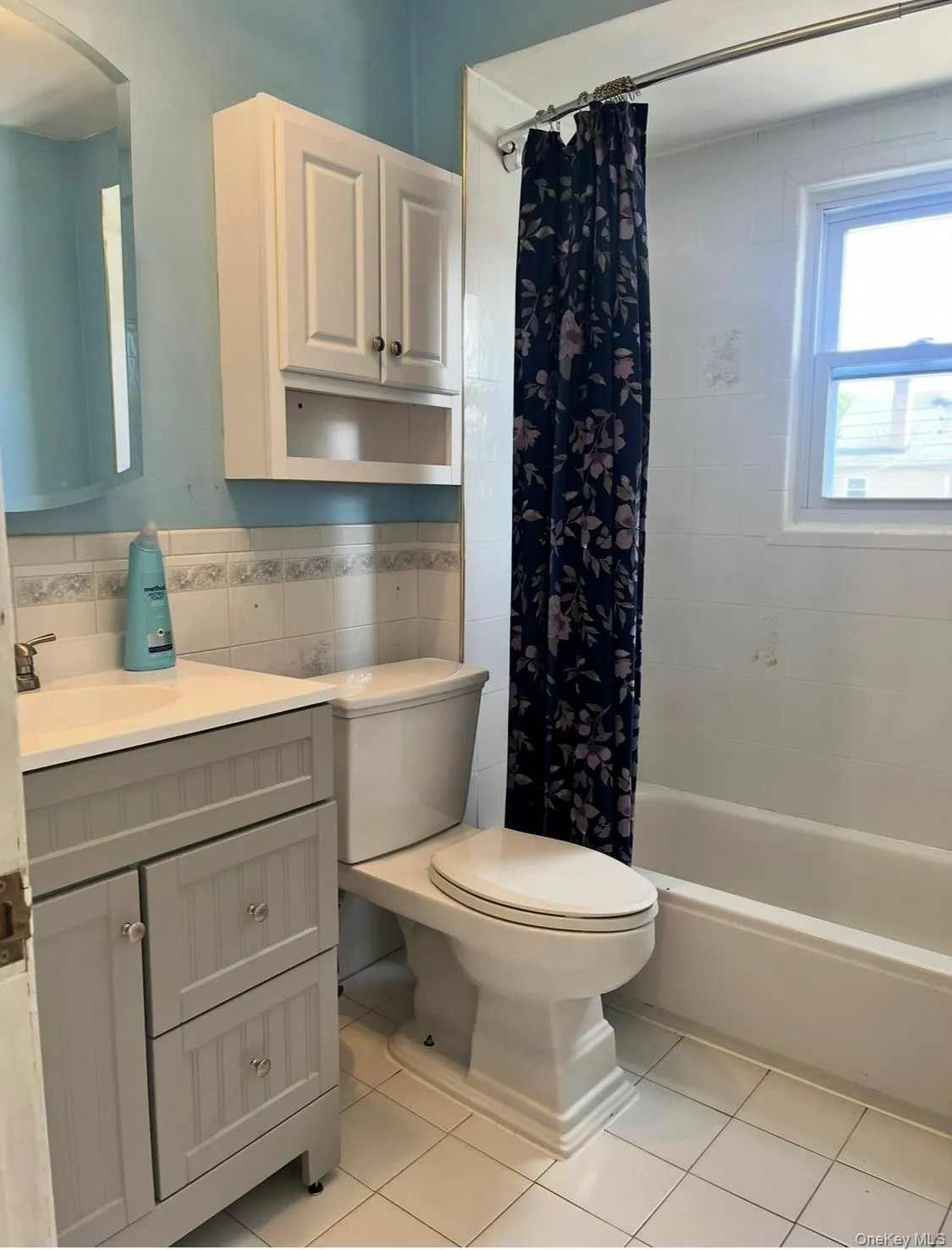 Bathroom featuring vanity, light tile patterned floors, shower / bathtub combination with curtain, tasteful backsplash, and tile walls Bathroom featuring vanity, light tile patterned floors, shower / bathtub combination with curtain, tasteful backsplash, and tile walls