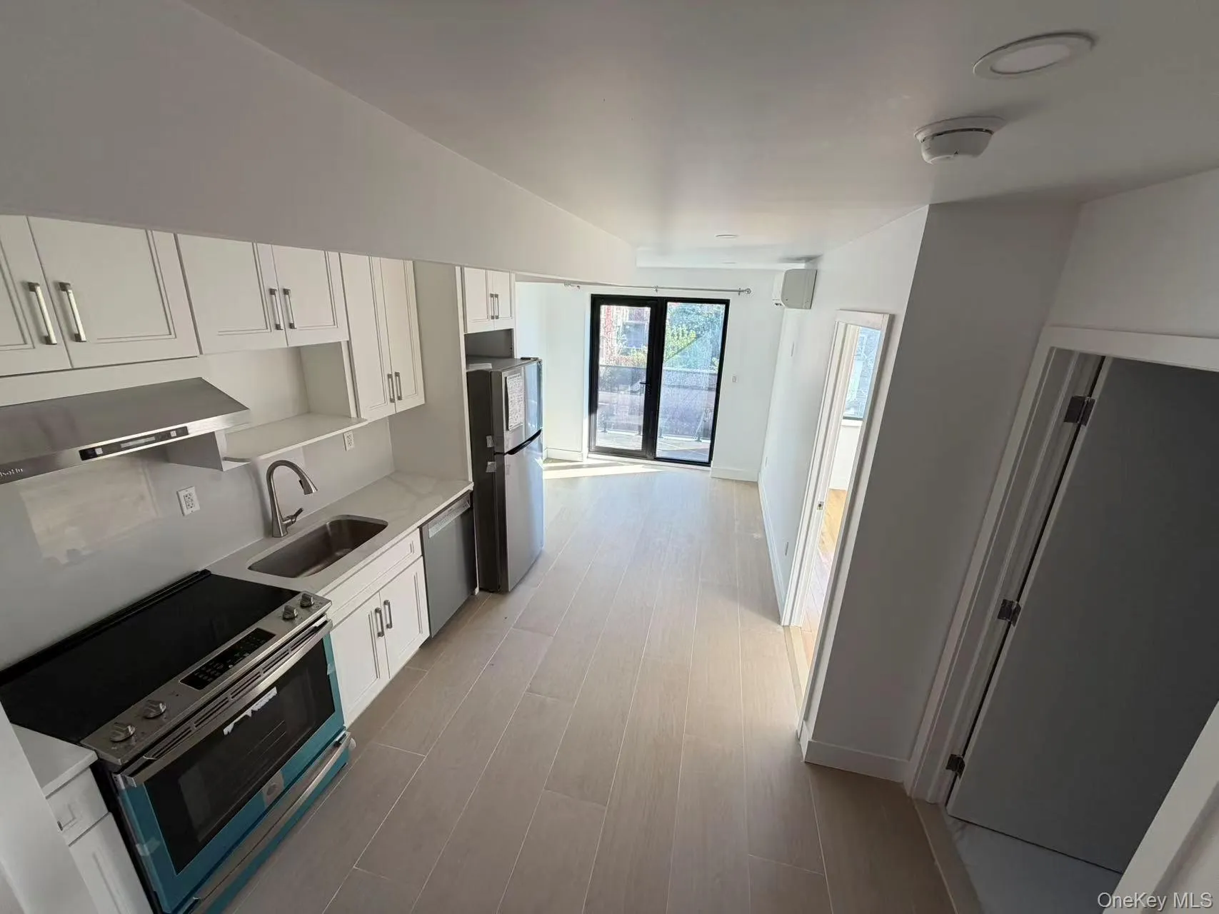 Kitchen featuring white cabinets, stainless steel appliances, under cabinet range hood, light wood finished floors, and light stone counters Kitchen featuring white cabinets, stainless steel appliances, under cabinet range hood, light wood finished floors, and light stone counters