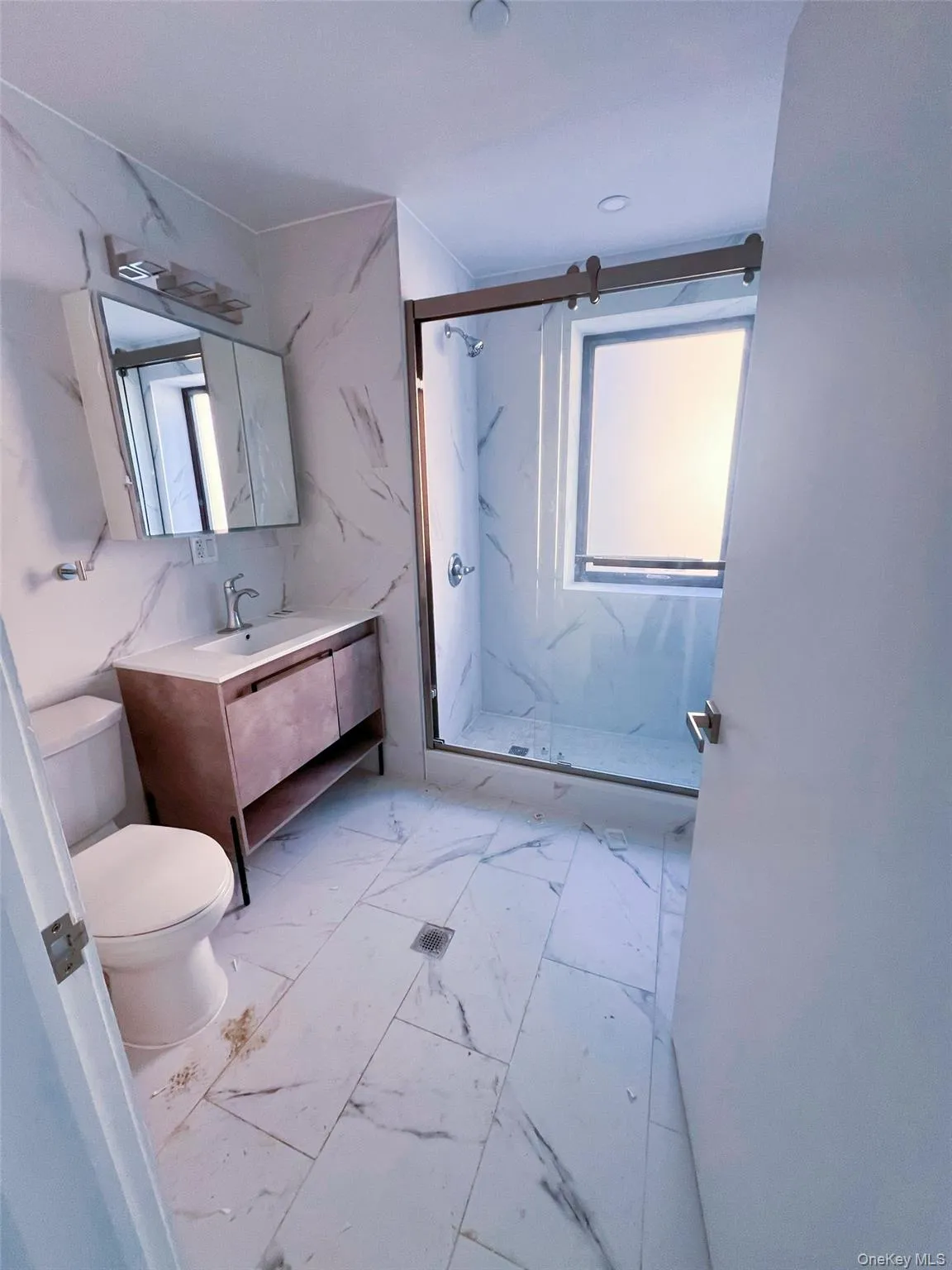 Bathroom with a marble finish shower, vanity, and light marble finish floors Bathroom with a marble finish shower, vanity, and light marble finish floors