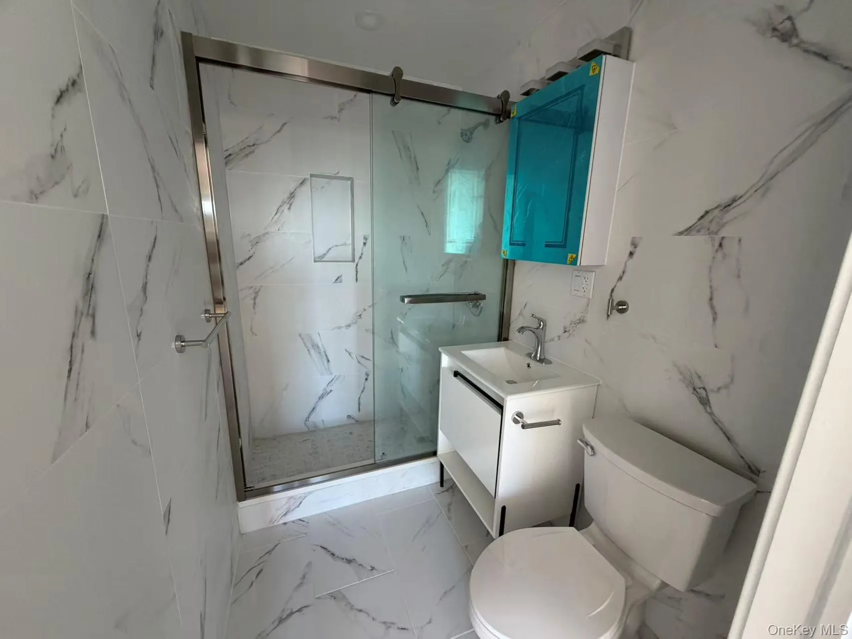 Full bathroom featuring vanity, a marble finish shower, stone wall, light marble finish flooring, and tile walls Full bathroom featuring vanity, a marble finish shower, stone wall, light marble finish flooring, and tile walls