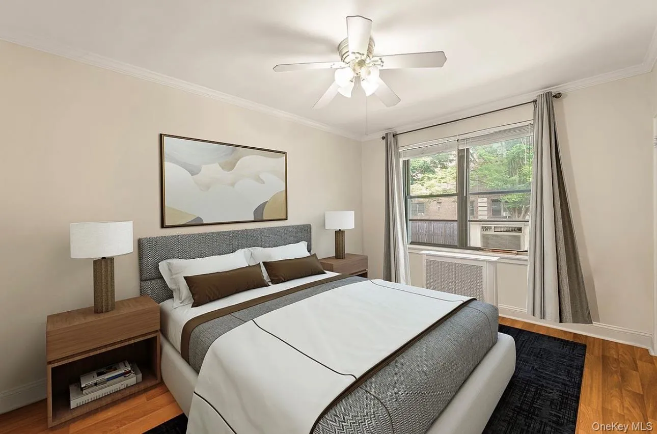Bedroom with ornamental molding, wood finished floors, ceiling fan, radiator, and cooling unit Bedroom with ornamental molding, wood finished floors, ceiling fan, radiator, and cooling unit
