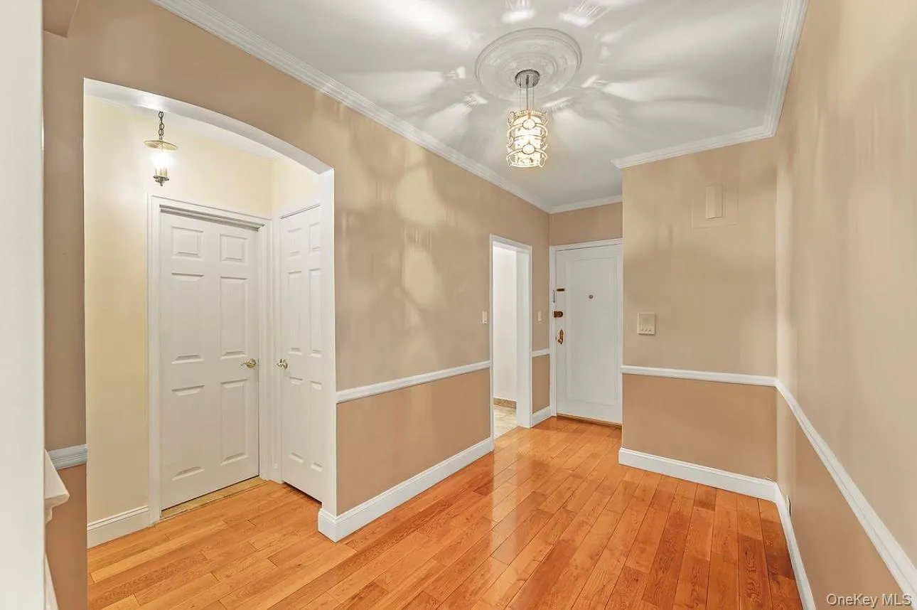 Corridor featuring ornamental molding, light wood-style floors, and arched walkways Corridor featuring ornamental molding, light wood-style floors, and arched walkways