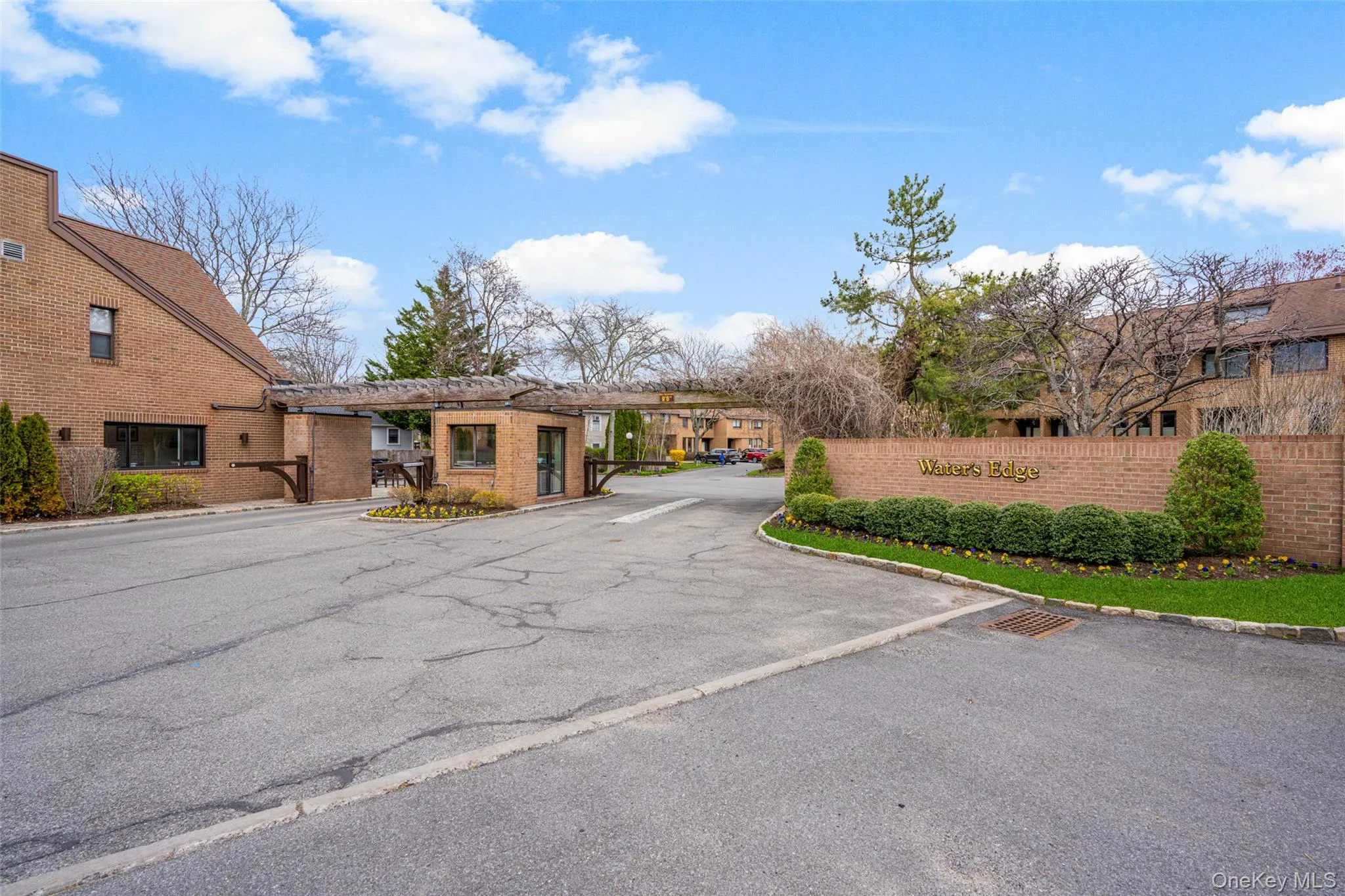 View of asphalt road featuring curbs, a residential view, and a gate View of asphalt road featuring curbs, a residential view, and a gate