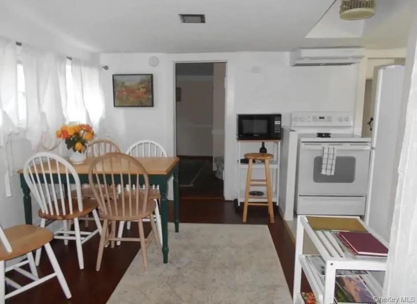 Kitchen with white appliances, dark wood-style floors, and a wall mounted AC Kitchen with white appliances, dark wood-style floors, and a wall mounted AC