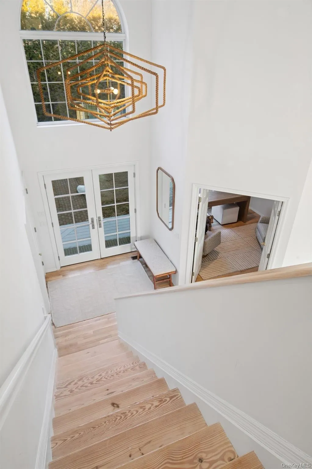Staircase with a high ceiling, french doors, wood finished floors, and a chandelier Staircase with a high ceiling, french doors, wood finished floors, and a chandelier