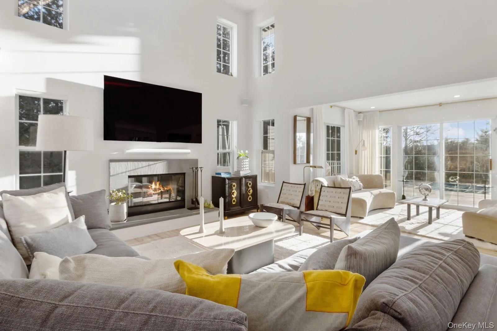 Living area with plenty of natural light, a glass covered fireplace, a high ceiling, and wood finished floors Living area with plenty of natural light, a glass covered fireplace, a high ceiling, and wood finished floors