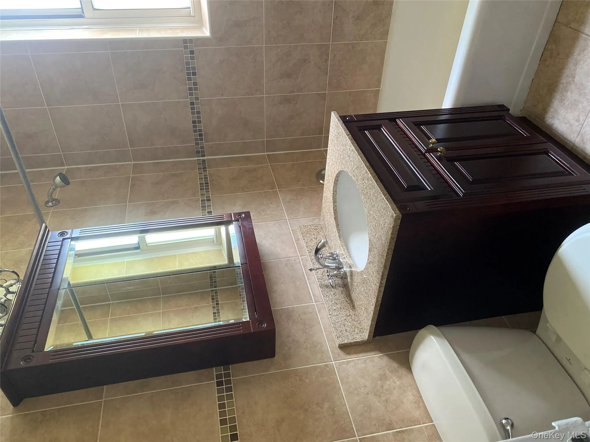 Bathroom with vanity, tile walls, plenty of natural light, light tile patterned floors, and shower / washtub combination Bathroom with vanity, tile walls, plenty of natural light, light tile patterned floors, and shower / washtub combination