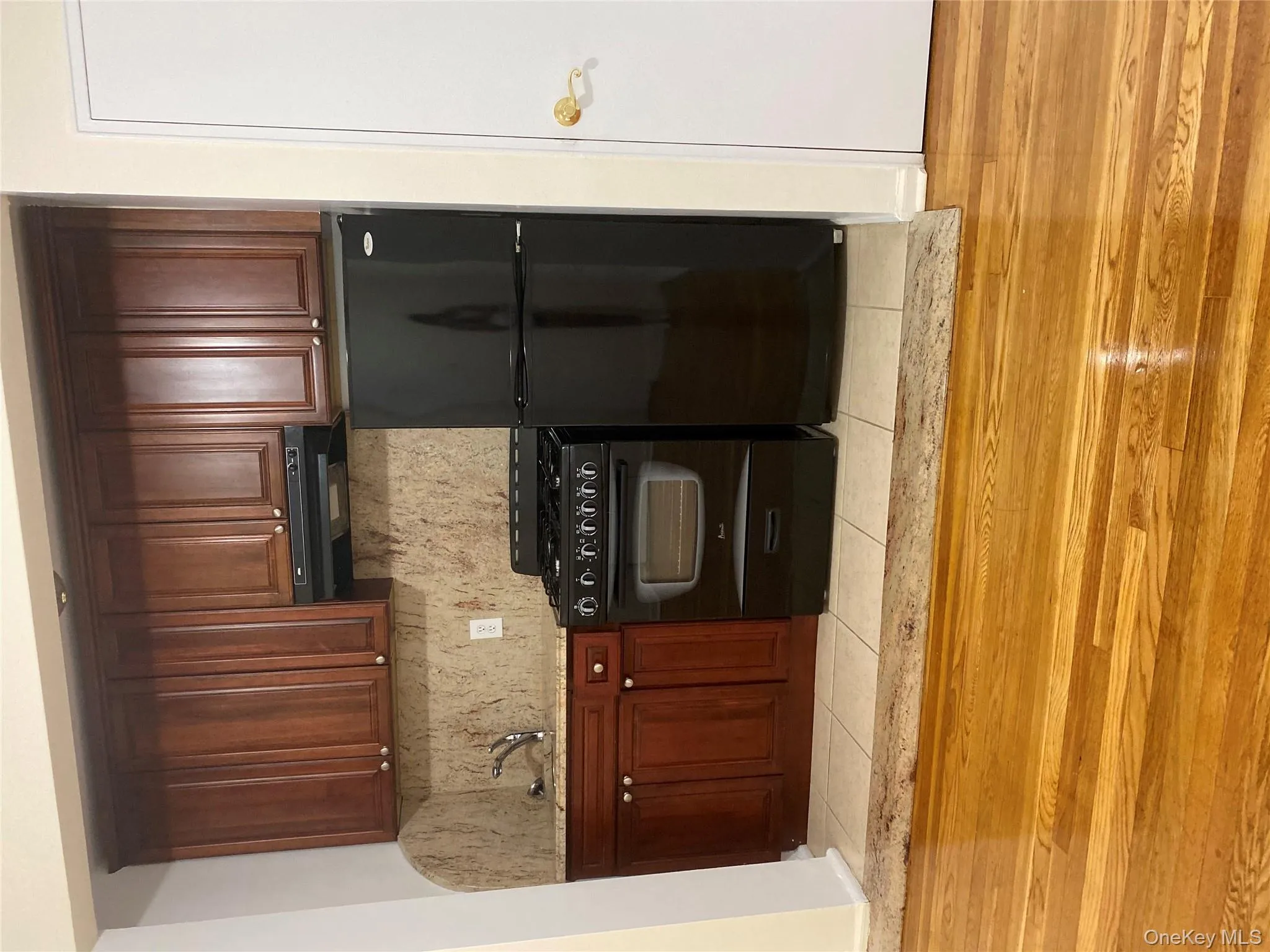 Kitchen with black gas range oven, refrigerator, light stone counters, ventilation hood, and tasteful backsplash Kitchen with black gas range oven, refrigerator, light stone counters, ventilation hood, and tasteful backsplash