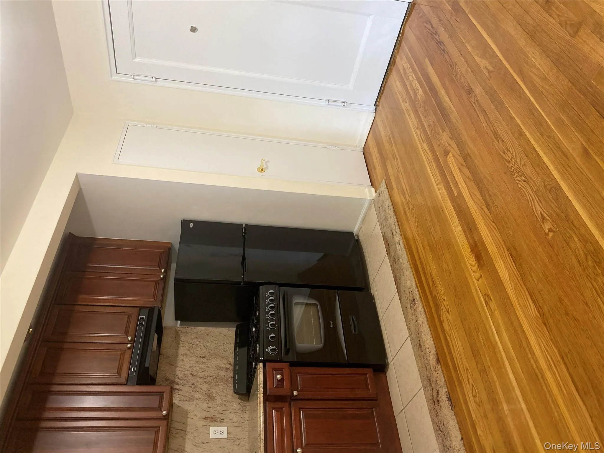 Kitchen with black stove, extractor fan, light stone counters, light wood-style floors, and freestanding refrigerator Kitchen with black stove, extractor fan, light stone counters, light wood-style floors, and freestanding refrigerator