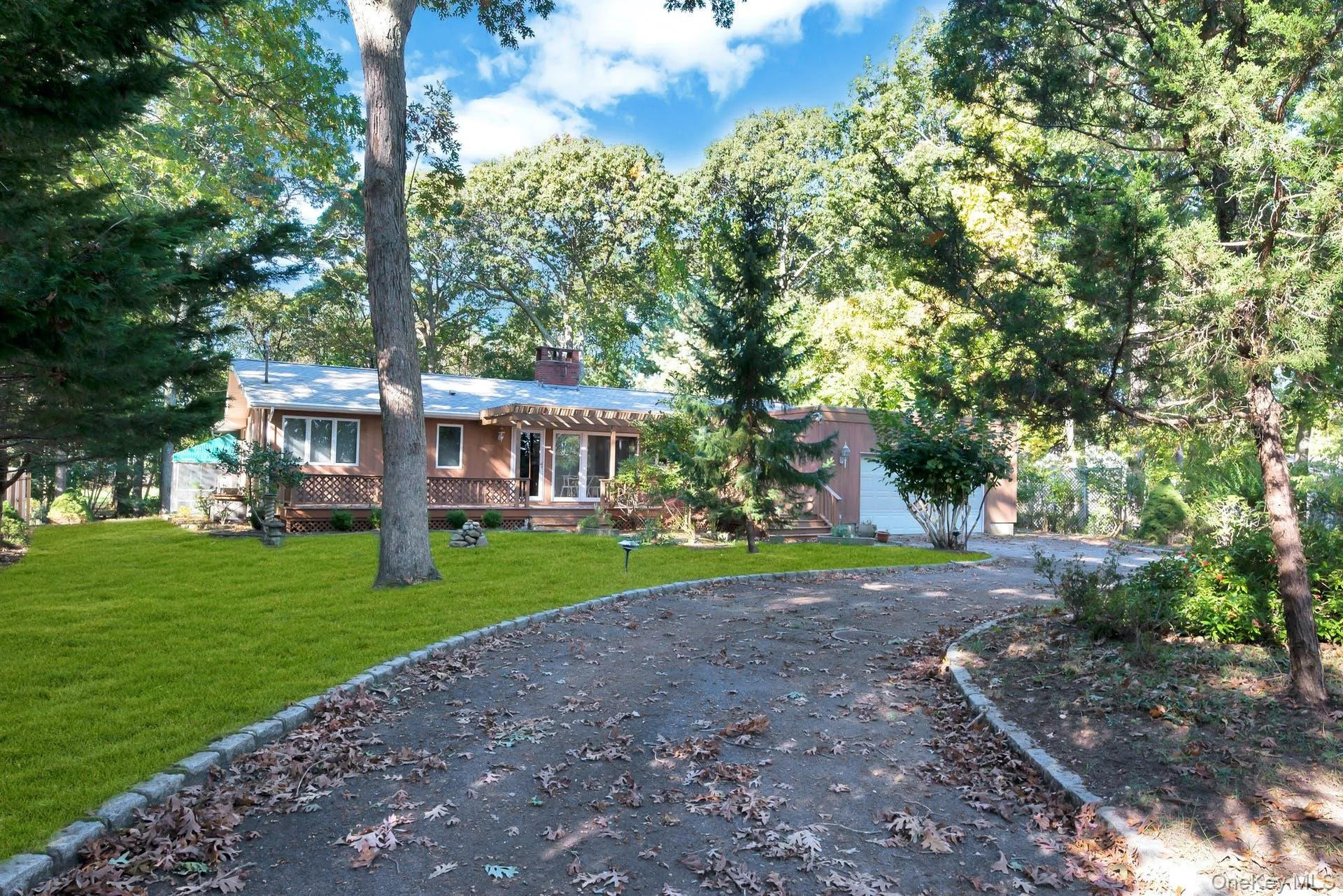 Ranch-style home with a front yard, a chimney, asphalt driveway, a garage, and view of scattered trees Ranch-style home with a front yard, a chimney, asphalt driveway, a garage, and view of scattered trees