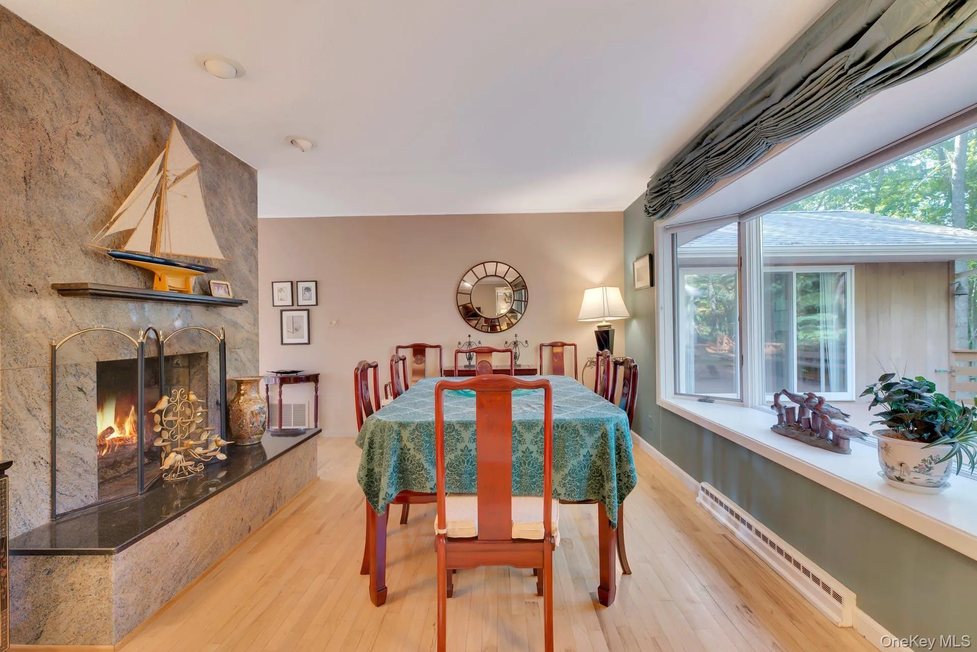 Dining area with a baseboard radiator, light wood finished floors, and a large fireplace Dining area with a baseboard radiator, light wood finished floors, and a large fireplace