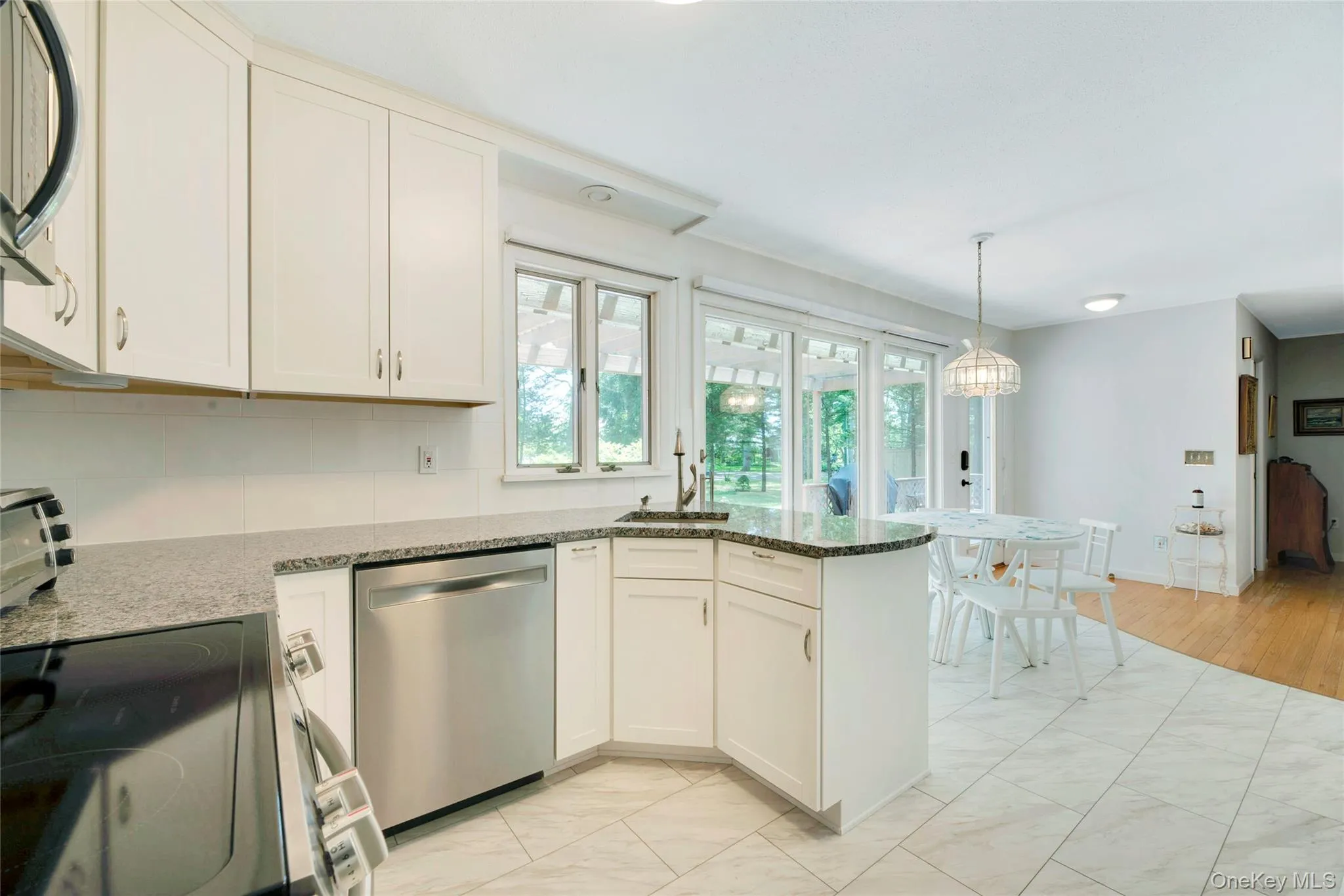 Kitchen featuring a peninsula, electric range oven, white cabinets, dishwasher, and dark stone countertops Kitchen featuring a peninsula, electric range oven, white cabinets, dishwasher, and dark stone countertops