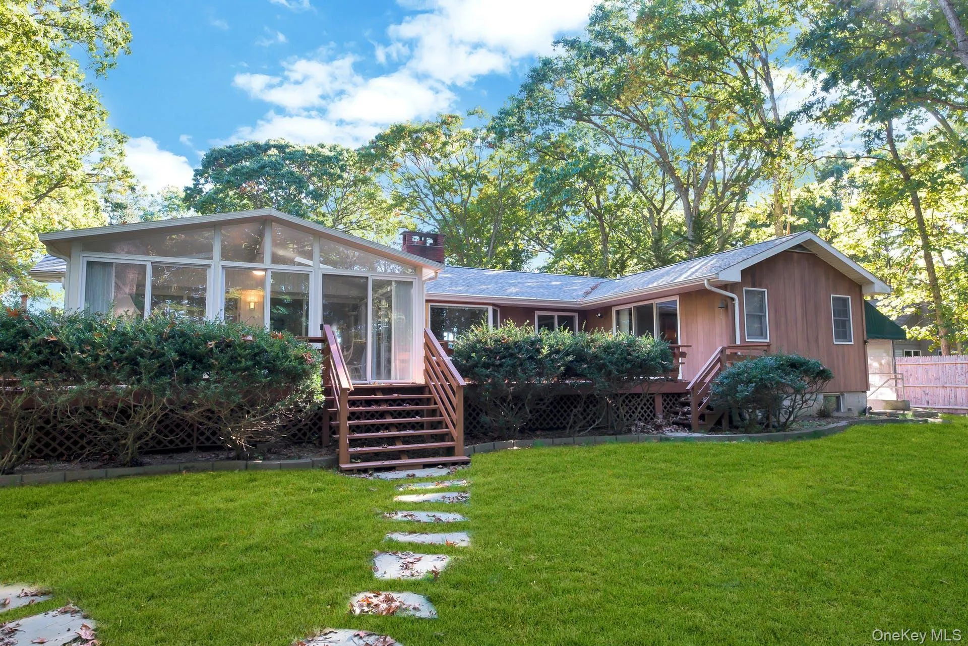 Rear view of property with a sunroom, stairs, and a deck Rear view of property with a sunroom, stairs, and a deck